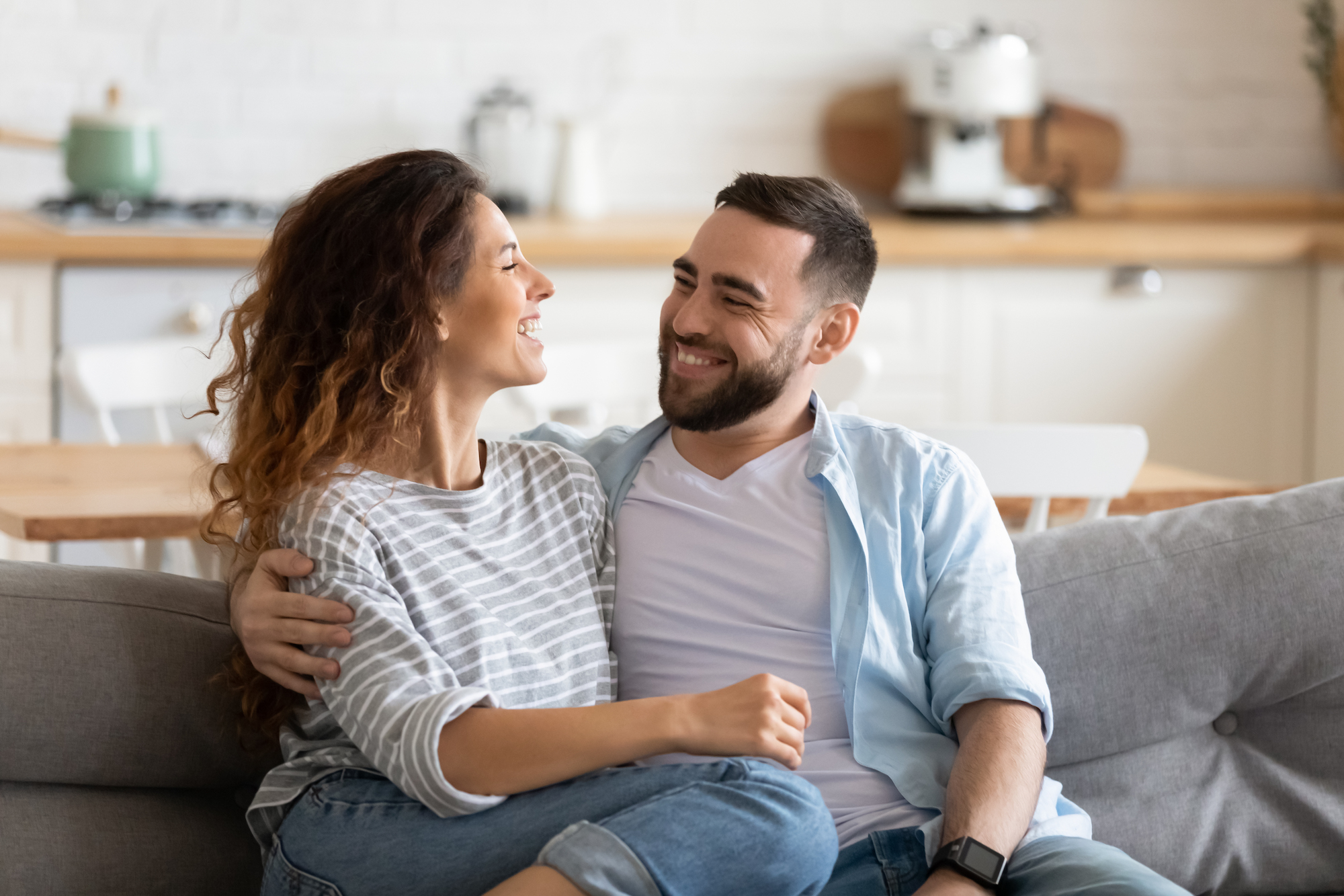Happy young couple of man and woman embracing. Young couple laughing on the couch