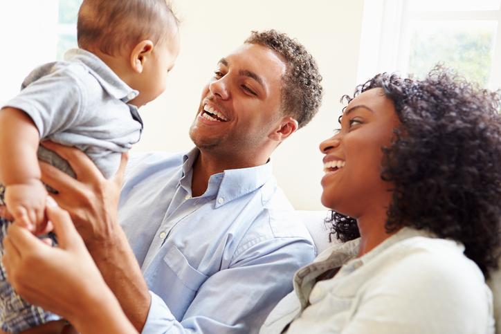 Young Family Playing With Happy Baby Son At Home